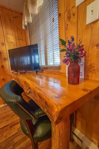 a wooden desk with a computer and a vase of flowers on it at Chinook Winds Lodge in Dubois