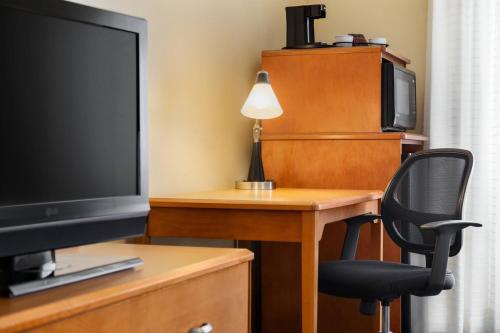 a room with a desk with a television and a chair at Fairfield Inn & Suites by Marriott Toledo Maumee in Maumee