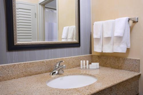 a bathroom with a sink and a mirror and towels at Courtyard by Marriott Oklahoma City Airport in Oklahoma City