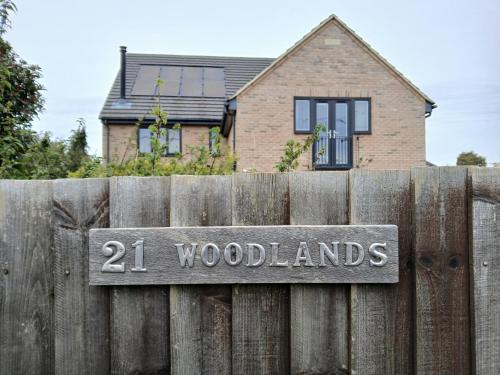 a sign on a wooden fence in front of a house at Woodlands Peaceful Bedrooms in Hemingford Grey