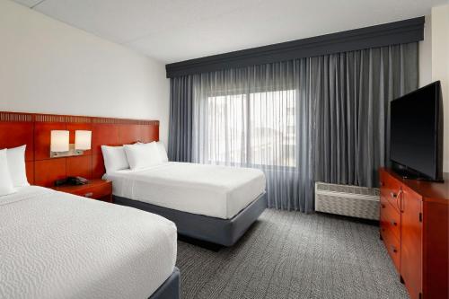 a hotel room with two beds and a flat screen tv at Courtyard by Marriott Minneapolis-St. Paul Airport in Mendota Heights