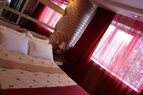 a bedroom with a bed and two windows with red curtains at Ust-Kamenogorsk Hotel in Ustʼ-Kamenogorsk