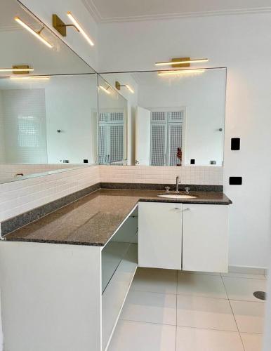 a white bathroom with a sink and a mirror at Santa Rita Pousada in Guarujá