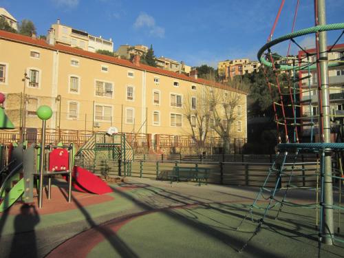 une aire de jeux en face d'un grand bâtiment dans l'établissement Appart F2 à 150 M de la plage avec parking privé, à Cerbère