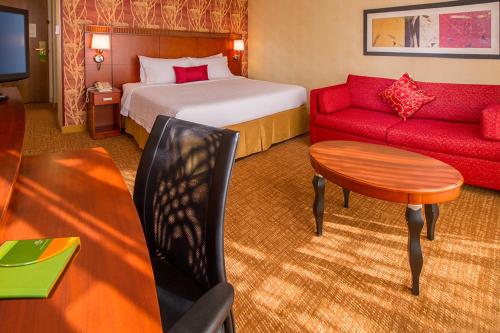 a hotel room with a bed and a red couch at Courtyard Manassas Battlefield Park in Manassas