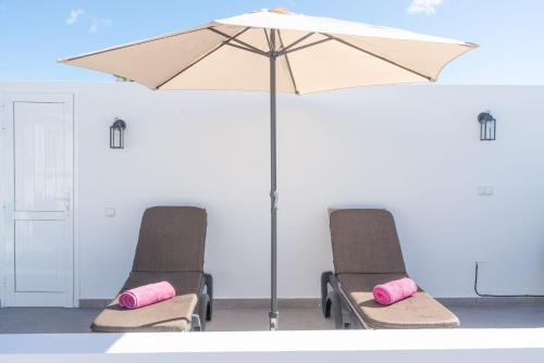 two chairs with pink pillows sitting under an umbrella at Apartment Orquidia - Rural Guest Apartment in Tías