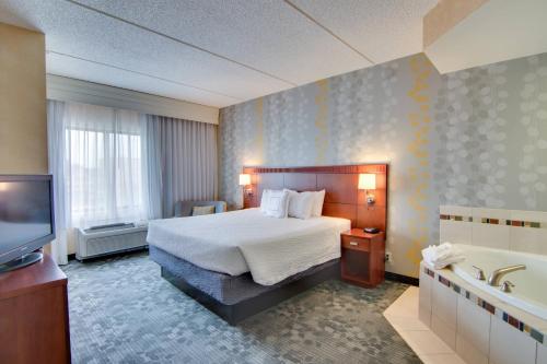 a hotel room with a bed and a tub and a television at Courtyard Rochester Mayo Clinic Area/Saint Marys in Rochester