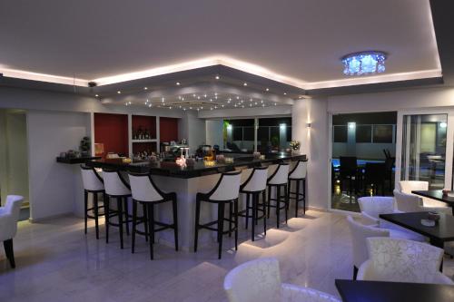 a bar in a restaurant with white stools at Ialysos City Hotel in Ialysos