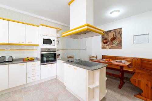 a kitchen with white cabinets and a wooden table at Apartment Orquidia - Rural Guest Apartment in Tías