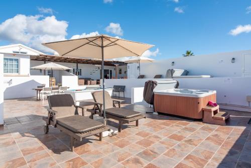a patio with a hot tub and chairs and an umbrella at Apartment Orquidia - Rural Guest Apartment in Tías