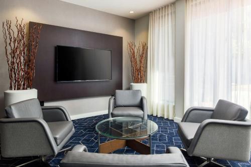 a living room with chairs and a table and a tv at Courtyard by Marriott Phoenix North in Phoenix