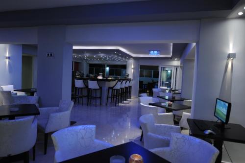 a restaurant with white chairs and tables and a bar at Ialysos City Hotel in Ialyssos