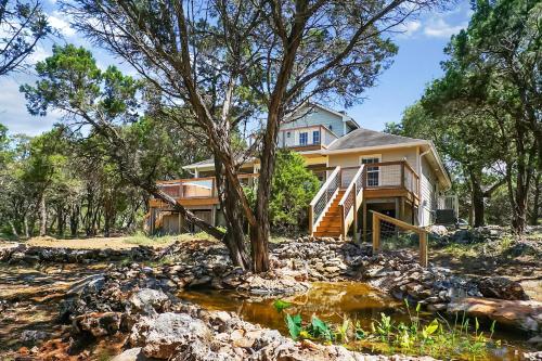 a house on a hill with a creek in front of it at Blue Spring Retreat in Wimberley