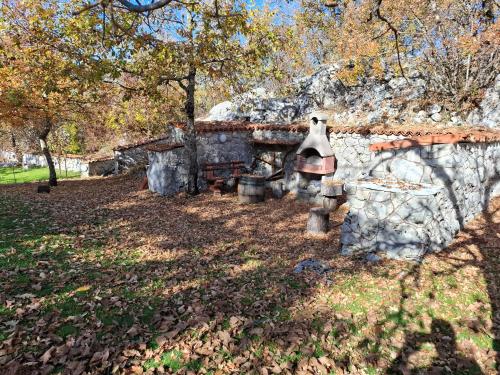 a stone house with a bell next to a wall at Guest House Vujošević in Podgorica