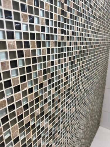 een badkamer met een betegelde muur en een douche bij Cozy Apartament Maspalomas in San Bartolomé