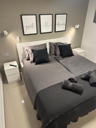 een slaapkamer met een groot bed met drie schilderijen aan de muur bij Cozy Apartament Maspalomas in San Bartolomé