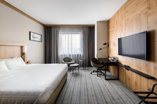 a hotel room with a bed and a flat screen tv at Courtyard by Marriott Warsaw Airport in Warsaw