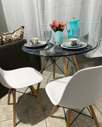 a glass table with two white chairs and two cups of coffee at Apartamento completo com garagem!Casa Taíba! in Fortaleza
