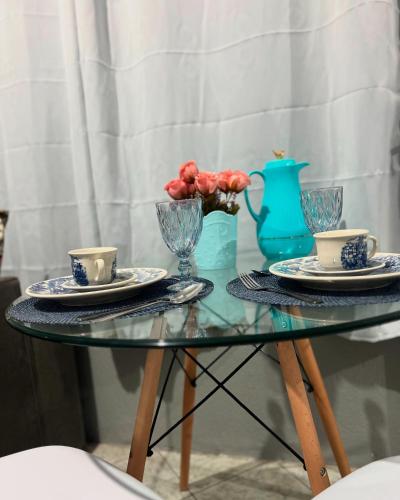 a glass table with two cups and plates and a vase at Apartamento completo com garagem!Casa Taíba! in Fortaleza