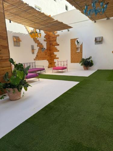a patio with purple chairs and a green lawn at Le style Damier in Sfax