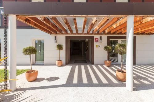 a building with potted trees in pots on a patio at Hotel Alienor in Langon