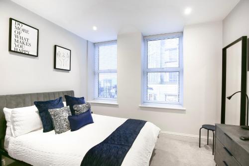 a bedroom with a bed and two windows at Churchill Square Views - Central - Modern 1 Bed Sleeps 4 in Brighton & Hove
