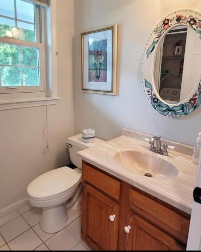 a bathroom with a toilet and a sink and a mirror at Tranquil Gardens Cape May Private Beach Steps Away in Cape May