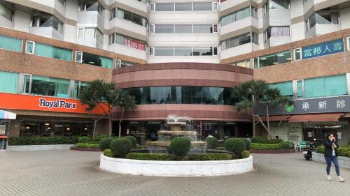 a woman walking in front of a building with a fountain at Large family room near Metro Taipei station for comfort and convenience, where 5 can relax and create unforgettable moments in Taipei
