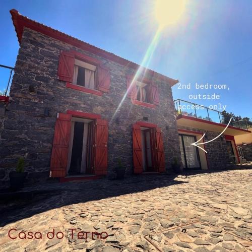 a building with red doors and a rainbow in the sky at Casa do terno com piscina in Arco da Calheta