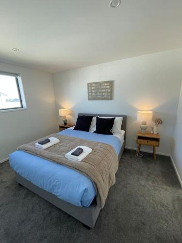 une chambre avec un grand lit avec deux serviettes dessus dans l'établissement Mohua Lane Urban Paradise, à Christchurch