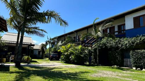 a building with a palm tree in front of it at Pousada Lagoa do Rosa in Praia do Rosa