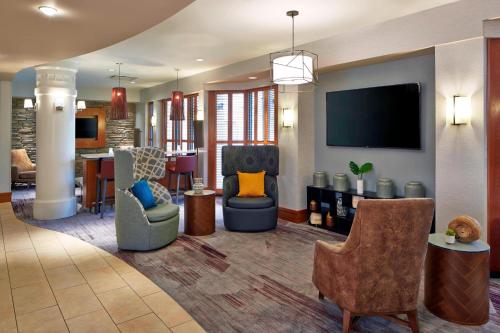 a lobby with chairs and a living room with a tv at Courtyard Rochester Brighton in Rochester