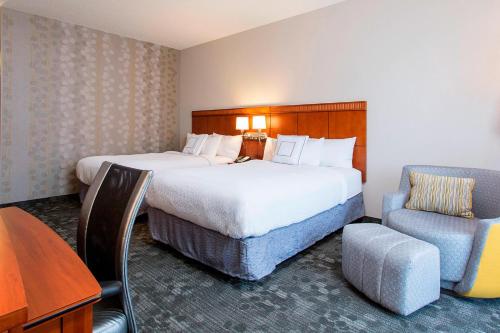 a hotel room with two beds and a desk and a chair at Courtyard Rochester Brighton in Rochester
