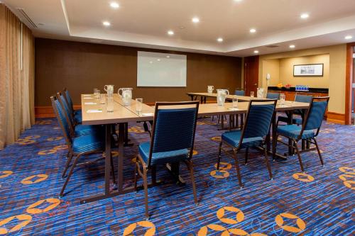 a conference room with tables and chairs and a screen at Courtyard Rochester Brighton in Rochester