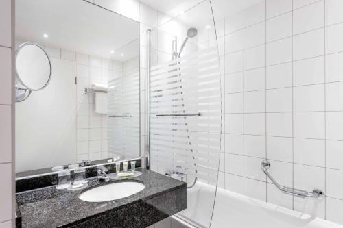 a bathroom with a sink and a shower at Courtyard by Marriott Munich City Center in Munich