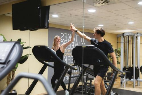a man and a woman in the gym giving each other a high five at Courtyard by Marriott Munich City Center in Munich