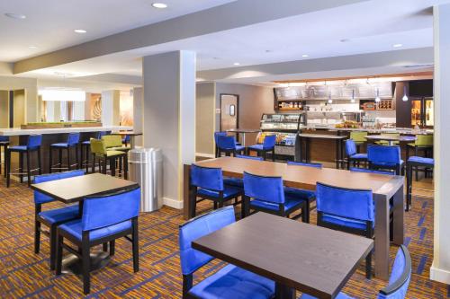 a restaurant with tables and chairs and a kitchen at Courtyard Tampa North / I-75 Fletcher in Tampa