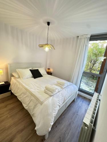 a bedroom with a bed with white sheets and a window at El Escondite De Las Margas in Sabiñánigo