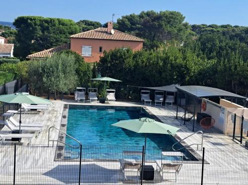une piscine avec des chaises et des parasols ainsi qu'une maison dans l'établissement Studio a 400 m plage et piscine, à Six-Fours-les-Plages