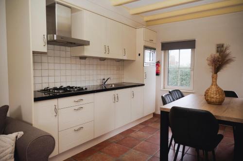 a kitchen with white cabinets and a table with chairs at Vakantiewoning de Boshoorn in Serooskerke