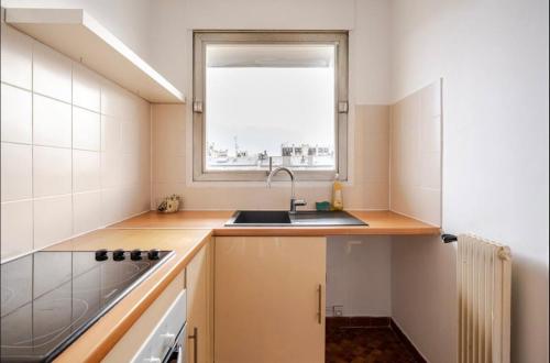 une petite cuisine avec un évier et une fenêtre dans l'établissement Piso en paris metro duplex Line 6, à Paris