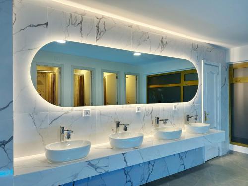a bathroom with four sinks and a large mirror at UNPLAN Hostel in Madrid