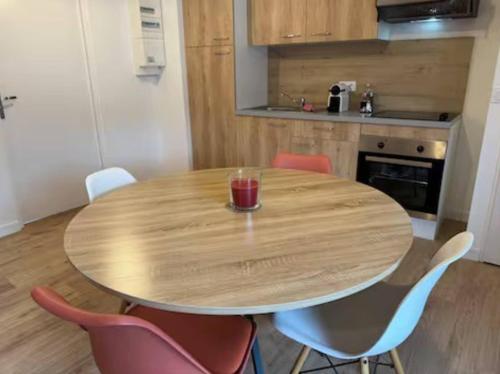 une table en bois dans une cuisine avec des chaises roses dans l'établissement Au cœur du village confortable, à Soucieu-en-Jarrest