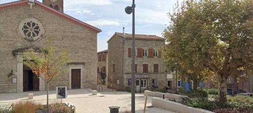 un vieux bâtiment en briques avec une tour d'horloge dans une rue dans l'établissement Au cœur du village confortable, à Soucieu-en-Jarrest