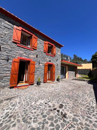 a stone building with orange doors on it at Casa do terno com piscina in Arco da Calheta
