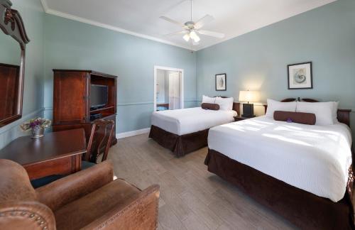 a hotel room with two beds and a television at Lavender Inn by the Sea in Santa Barbara