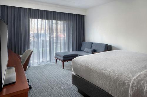 a hotel room with a bed and a chair and a window at Courtyard by Marriott Silver Spring North/White Oak in Silver Spring