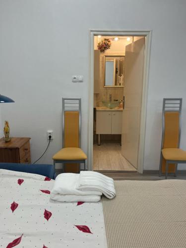 a bedroom with a bed and two chairs and a bathroom at Életfa Pihenő Apartman in Tapolca