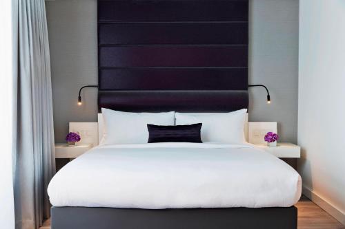 a bedroom with a large white bed with a black headboard at Renaissance Vienna Schönbrunn Hotel in Vienna