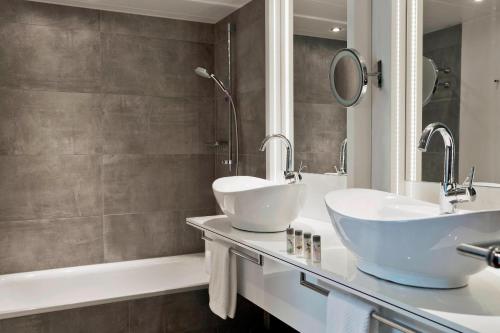 a bathroom with two sinks and a tub at Renaissance Vienna Schönbrunn Hotel in Vienna